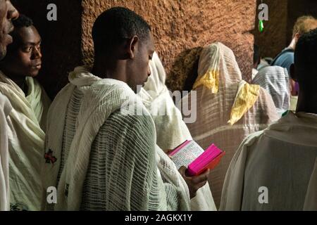 Ethiopia, Amhara Region, Lalibela, Bet Gabriel Rafael, worshipper holding Amharic language gospel during mass Stock Photo