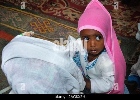 Ethiopia, Amhara Region, Lalibela, Bet Gabriel Rafael, worshipper holding young child in arms during mass Stock Photo