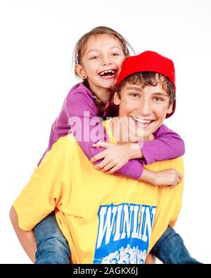 happy teenage boy giving his little sister  piggy back ride - isolated on white Stock Photo