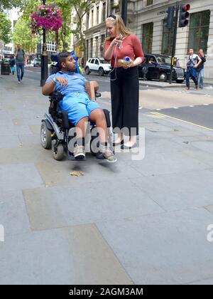 London, England, UK. Young man in a wheelchair with his carer Stock Photo