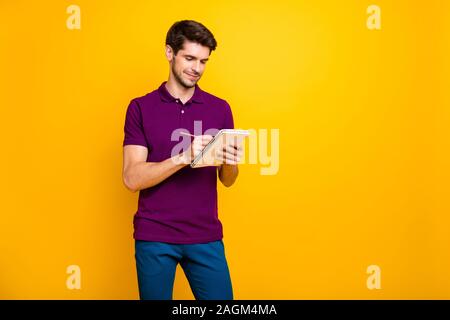 Portrait of his he nice attractive cheerful cheery focused concentrated guy making writing notes memo isolated over bright vivid shine vibrant yellow Stock Photo