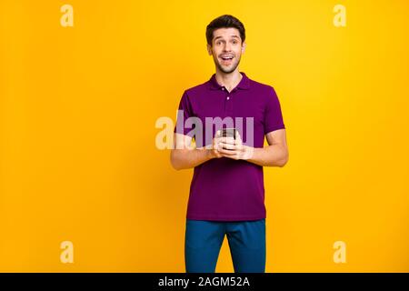 Portrait of his he nice attractive addicted delighted cheerful cheery guy wearing violet shirt using digital device modern technology isolated on Stock Photo