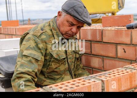 Elderly bricklayer works on house construction Stock Photo