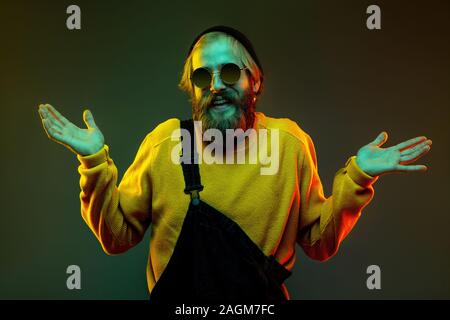 Caucasian woman's portrait on gradient studio background in neon light. Beautiful male model with hipster style in glasses. Concept of human emotions, facial expression, sales, ad. Wondered, astonished. Stock Photo