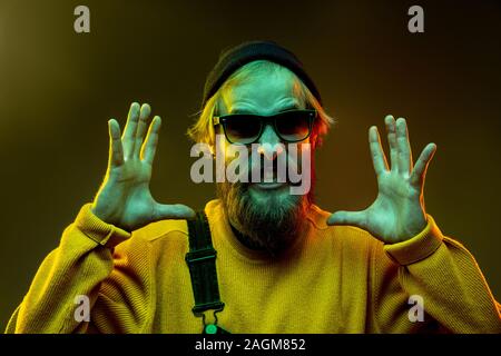 Caucasian woman's portrait on gradient studio background in neon light. Beautiful male model with hipster style in glasses. Concept of human emotions, facial expression, sales, ad. Shocked calling. Stock Photo