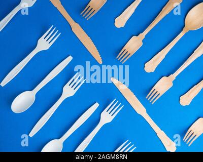 harmful plastic cutlery and eco friendly wooden cutlery. plastic free concept on blue background Stock Photo