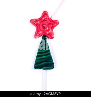Two colorful lollipops as Christmas tree on white background. Bright red star and green fir festive concept. Stock Photo