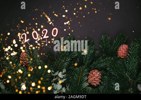 Numbers 2020 with branches of a Christmas tree on a black background Stock Photo