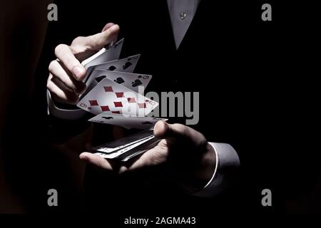 Magician shuffling cards with the spotlight on it Stock Photo