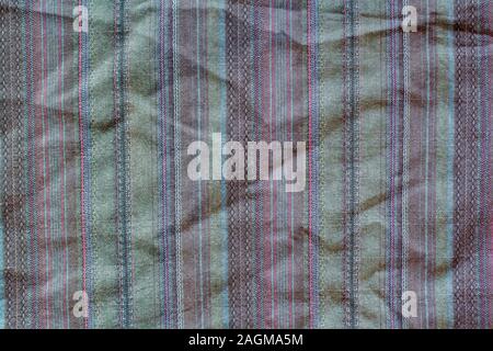 Fabric texture with multi-colored vertical stripes. A lot of stitches on the fabric. Red, green, brown colors. Stock Photo