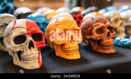 A collection of multi-colored ceramics skulls, close-up. Hand painted skulls for Halloween and Mexican Day of the dead decoration. Stock Photo