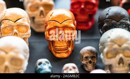 A collection of multi-colored ceramics skulls, close-up. Hand painted skulls for Halloween and Mexican Day of the dead decoration. Stock Photo
