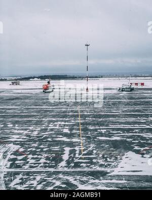 Vertical shot of a snowy airplane airstrip with  a couple of airplanes on a cloudy day Stock Photo