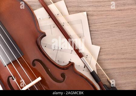 Violin body and bow with sheet music on wood table. Top view. Horizontal composition. Stock Photo
