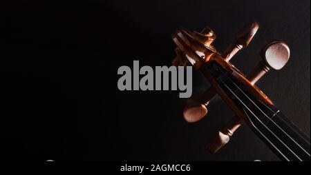 Violin pegbox and bow on black textured table Top view. Horizontal panoramic composition. Stock Photo