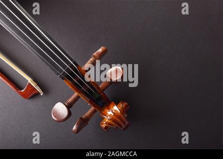 Violin pegbox and bow on black textured table Top view. Horizontal composition. Stock Photo