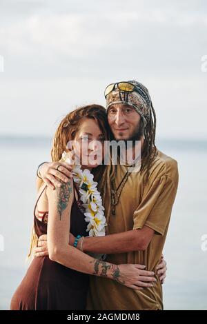 Portrait of happy middle-aged loving embracing couple looking at camera when standing on the beach Stock Photo
