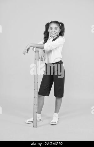 Exploring stem. Geometry school subject. School adorable student study geometry. Kid school uniform hold ruler. Education and school concept. Sizing and measuring. Pupil cute girl with big ruler. Stock Photo