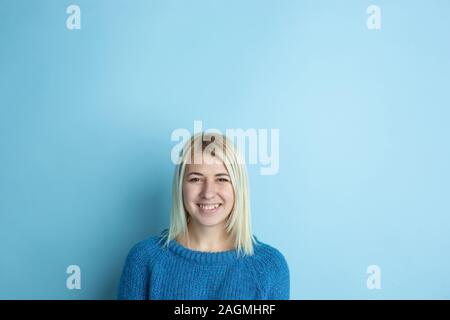 Portrait of young caucasian woman looks dreamful, cute and happy. Thinking, wondering, dreaming on blue studio background. Copyspace for your ad. Concept of future, target, dreams, visualisation. Stock Photo