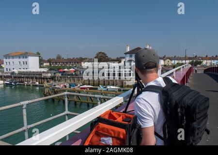 A young photographer preparing to take photos from a bridge over a river. Stock Photo