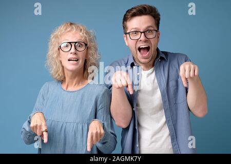 Mature woman and young man show index finger ion copy space for your text Stock Photo