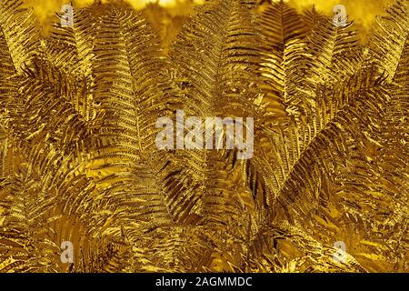 Abstract golden fern leaves background close up, fantastic gold colored bracken foliage texture decorative fantasy yellow tropical frond leaf pattern Stock Photo