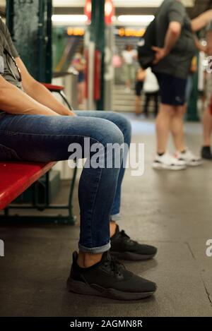 closeup of a young caucasian man, wearing casual clothes, sitting in a wooden bench in an underground station Stock Photo