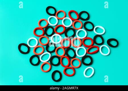 A scattering of multi colored elastic bands on a blue turquoise background Stock Photo