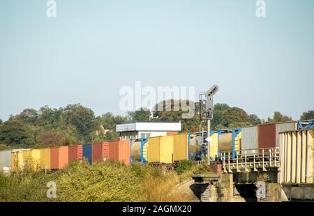 A freight train travels across the British countryside taking goods from A to B. Stock Photo