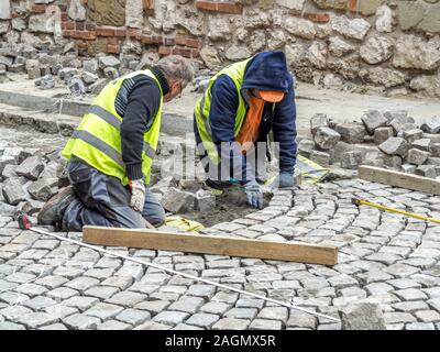Street workers lay stones by hand to form new street in Krakow, Poland. Stock Photo