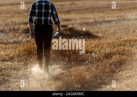 cropped view of senior man holding rake while walking wheat field Stock Photo