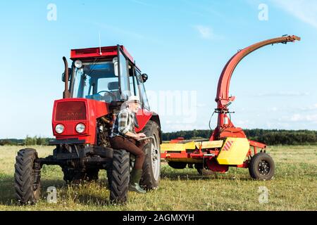 senior farmer using digital tablet near red tractor Stock Photo