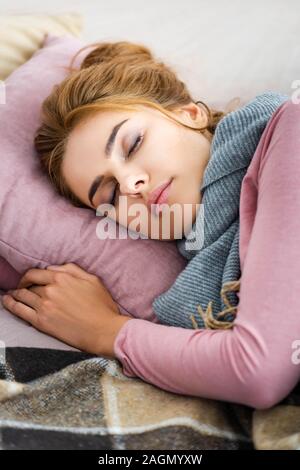 attractive and ill woman with grey scarf sleeping on bed Stock Photo