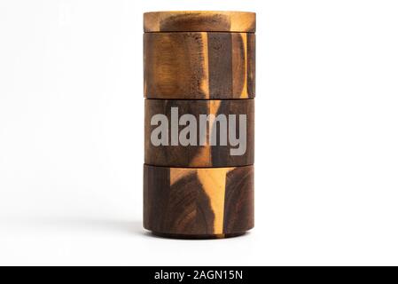 A towering three-level set of bamboo wood condiments vessel with lid cover set on a plain white background. Stock Photo