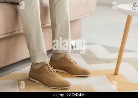 cropped view of man in stylish leather shoes sitting on sofa Stock Photo
