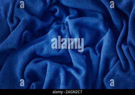 Closeup classic blue macro texture of blue fleece material fabric or clothing. Toned trendy 2020 year color background with wrinkles and folds. Dark b Stock Photo