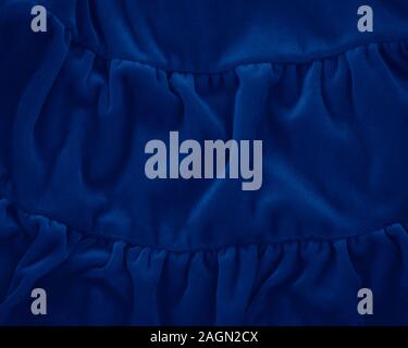 Closeup classic blue macro texture of blue velvet material fabric or clothing. Toned trendy 2020 year color background with wrinkles and folds. Dark b Stock Photo