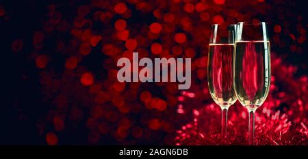 Two champagne glasses on sparkling red bokeh background. Celebration toast flutes. Valentine's day dinner invitation. Christmas and new year holiday p Stock Photo