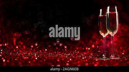 Two champagne glasses on sparkling red bokeh background. Celebration toast flutes. Valentine's day dinner invitation. Christmas and new year holiday p Stock Photo