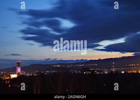 Beautiful dramatic sunset evening with fast moving clouds over town. Long exposure. Banska Bystrica, Slovakia, Central Europe.  Darkening sky. Stock Photo