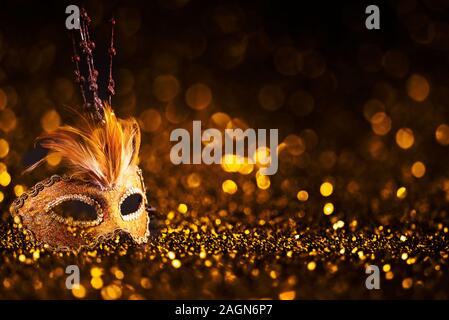 Luxury venetian mask on dark godlen bokeh background. New year and christmas party celebration design banner. Carnival masquerade fantasy costume ball Stock Photo