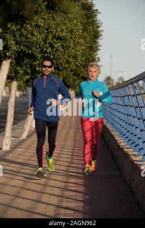 Two happy athletes jogging on the city street, Alicante, Spain Stock Photo