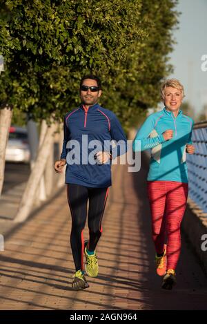 Two happy athletes jogging on the city street, Alicante, Spain Stock Photo