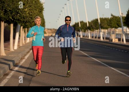 Two happy athletes jogging on the city street, Alicante, Spain Stock Photo