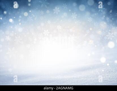 Snowflakes and snowfall on a cold blue winter background and a powder snow ground. Winter seasonal material. Stock Photo