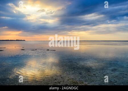 The light of the sun in the cloudy sky reflected in the ocean water below Stock Photo