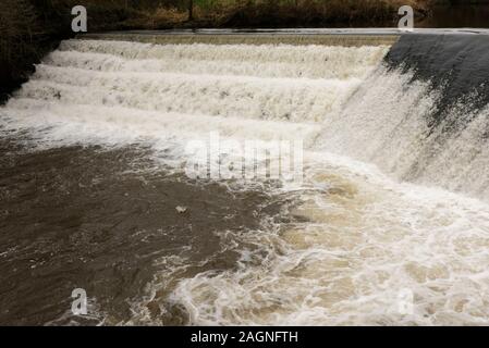 Fast flowing river irwell plunging over weir and aerating river downstream in burrs country park bury lancashire uk Stock Photo