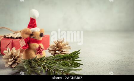 Little toy Christmas mouse, gift and decorations on a gray table. Christmas composition with the symbol of 2020 according to the Chinese horoscope Stock Photo