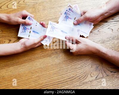 Hands of a man giving fifthy thousand pesos bills to a Young over a table Stock Photo