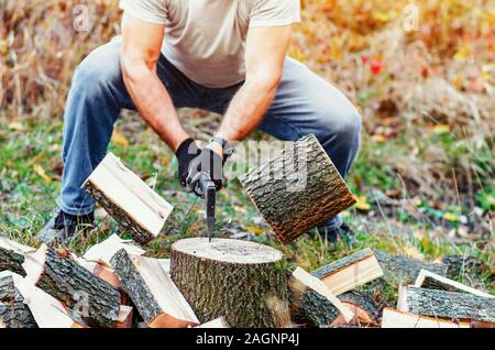 Man with strong hands chopping wood with an ax pieces fly apart. Stock Photo